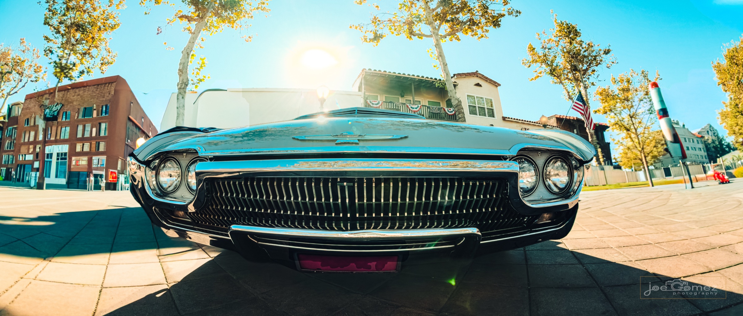 Wide low-angle study of a classic chrome grille reflecting a city street