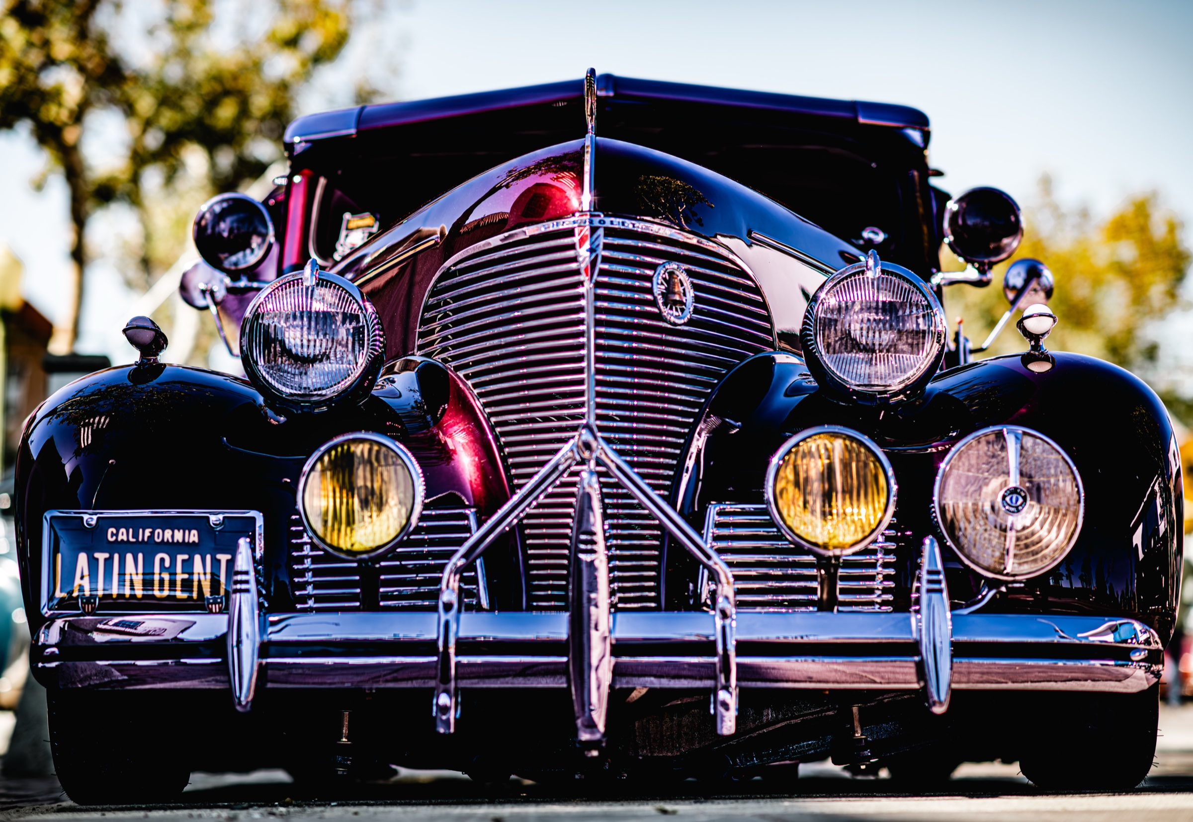 Classic dark automobile with an ornate chrome grille and multiple headlights