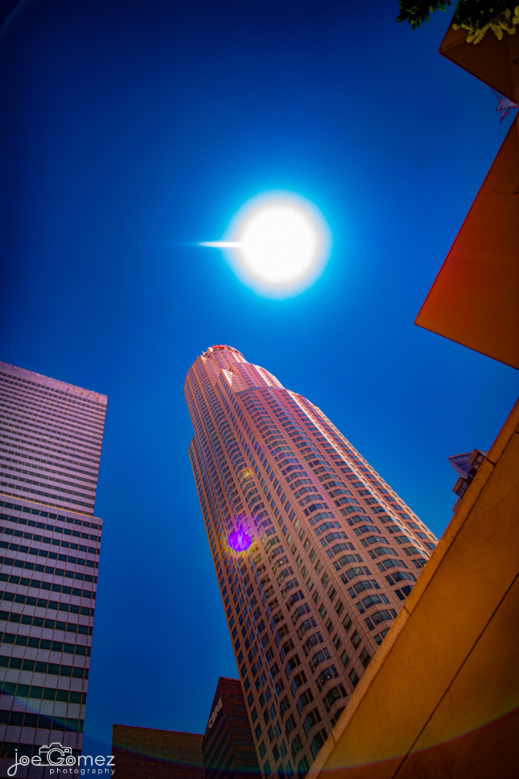 Upward architectural view of a sunlit tower beneath a blue sky