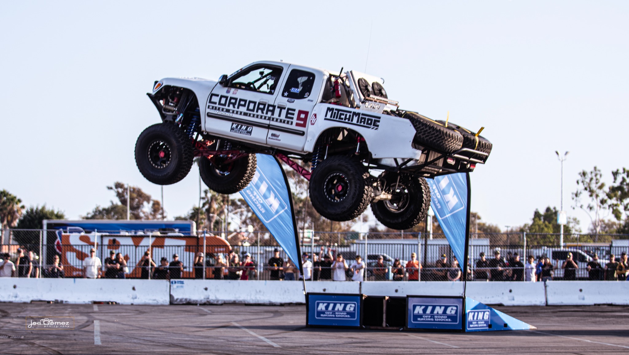 A white off-road truck airborne during an arena demonstration