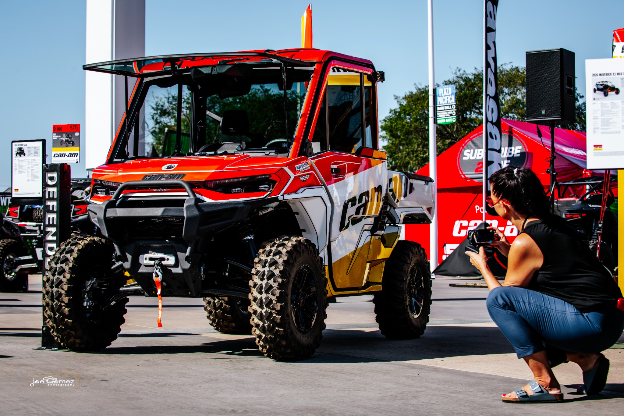 A visitor photographs a vehicle beside the Can-Am display