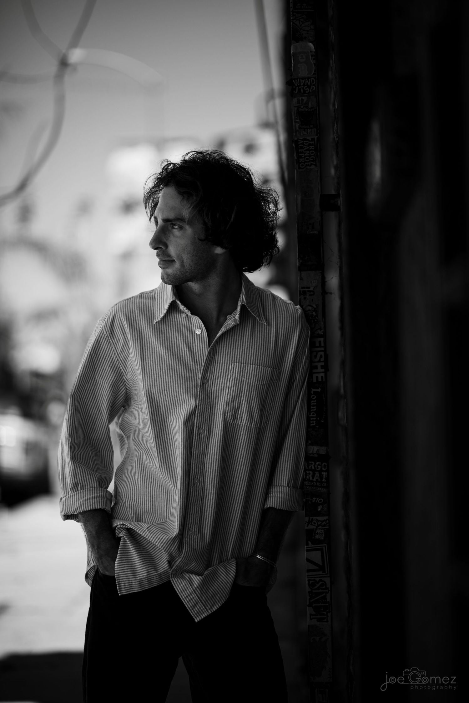 Moody black-and-white environmental portrait of a male creative in dramatic window light.