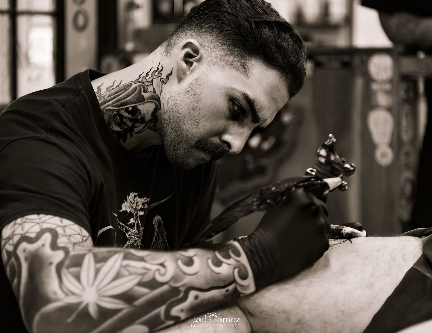 Black-and-white documentary portrait of a tattoo artist creating detailed body art at Ganga Tattoo in Los Angeles.