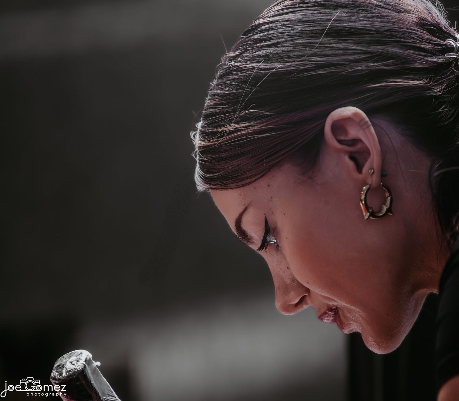 Close profile portrait of a woman holding a tattoo machine in soft cinematic light, photographed for a Southern California editorial story.