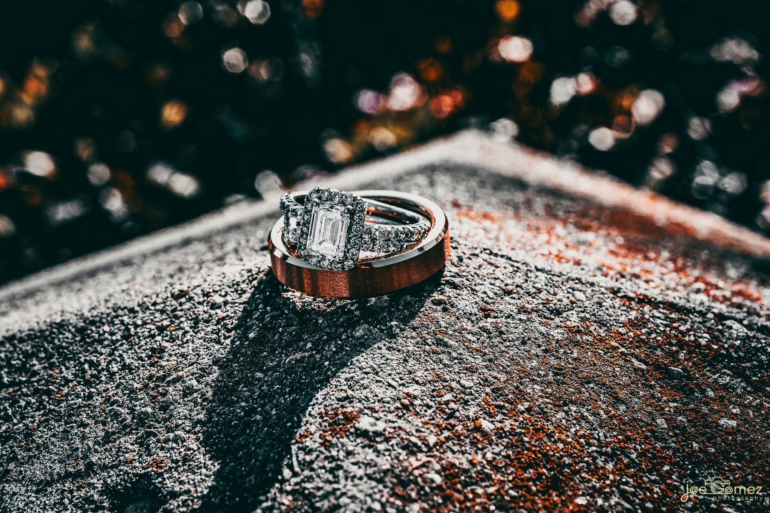 Macro wedding detail photograph of diamond rings with dramatic texture and shallow depth of field.
