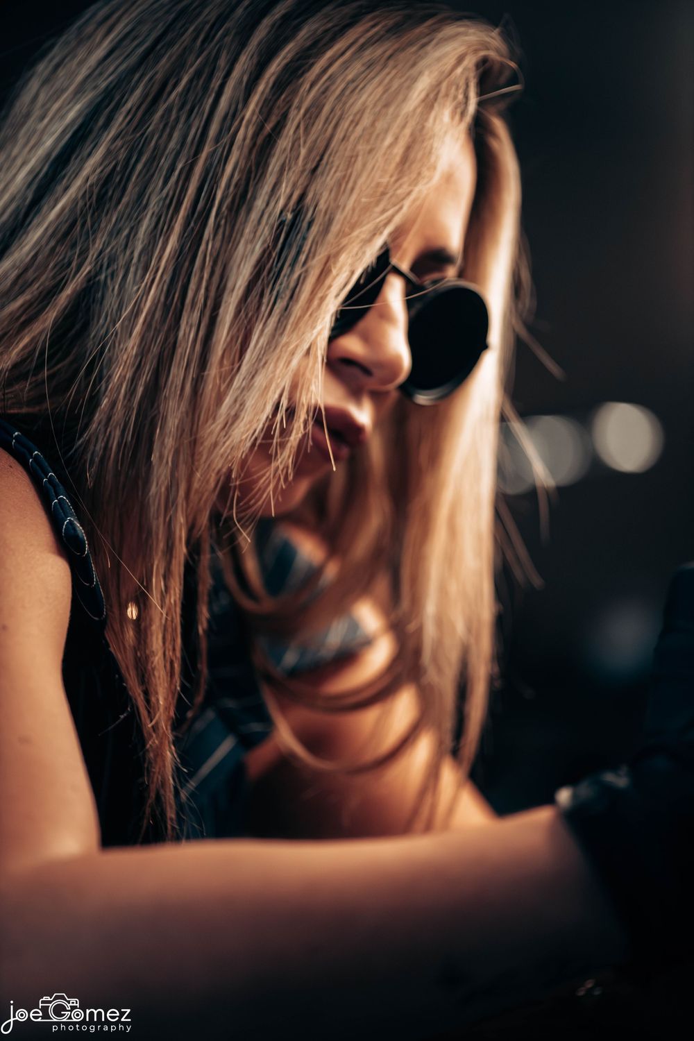 Close editorial portrait of a woman in sunglasses with cinematic side lighting, photographed in Los Angeles by Joe Gomez.