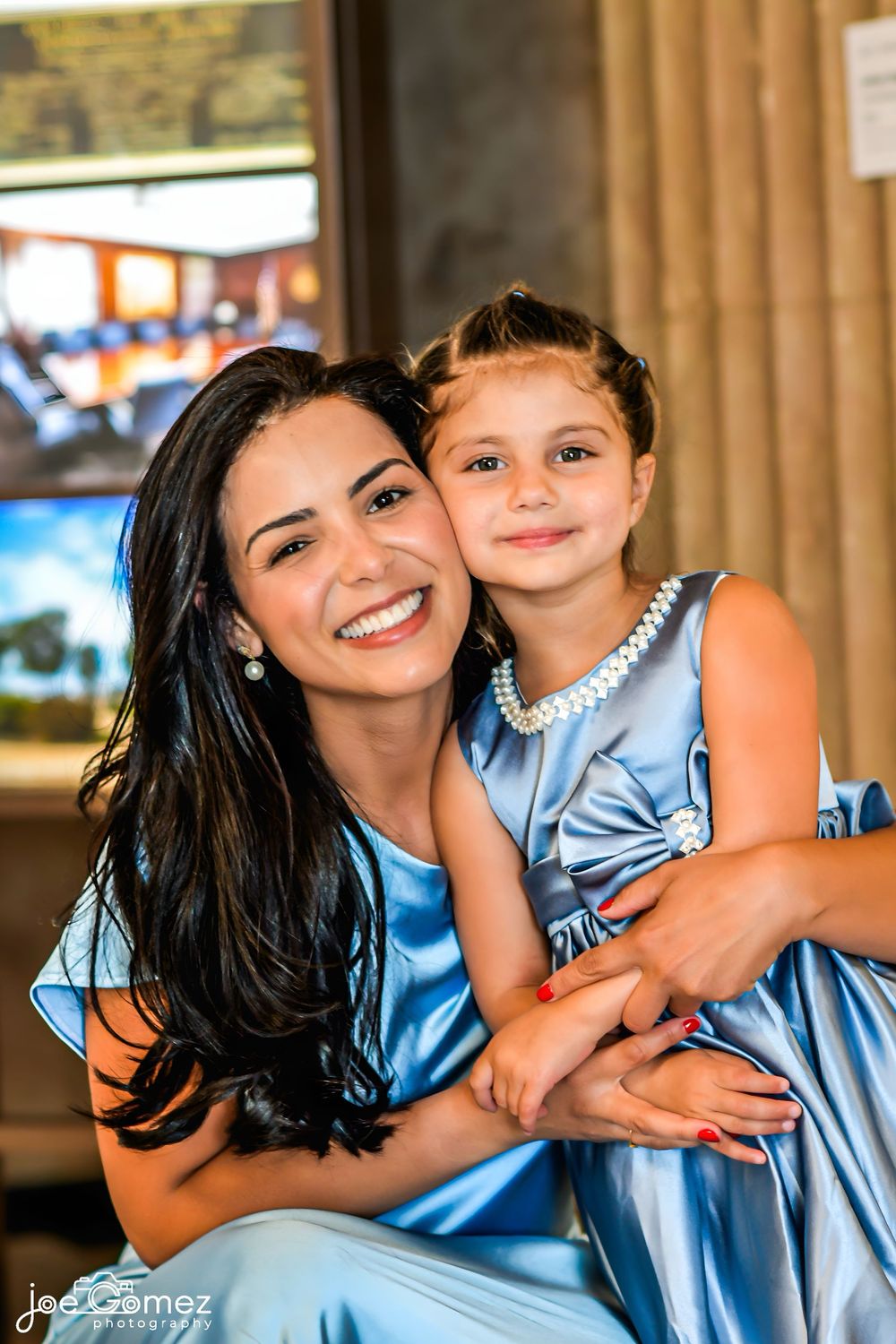 Candid portrait of a bridesmaid and flower girl embracing during a San Diego wedding celebration.