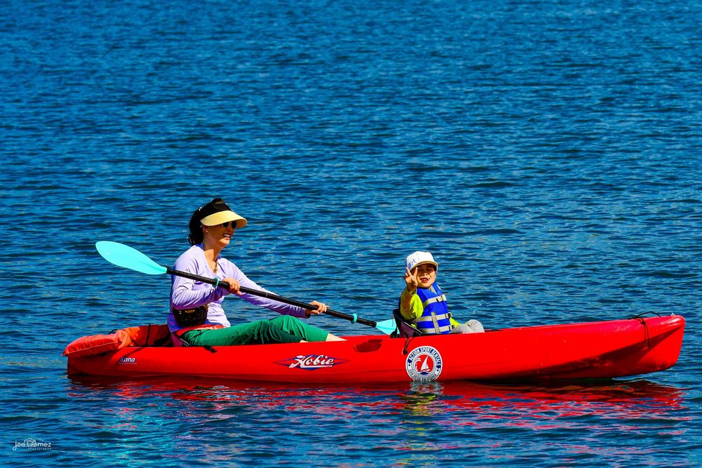 Lifestyle family photograph of a parent and child kayaking together on a Southern California lake.